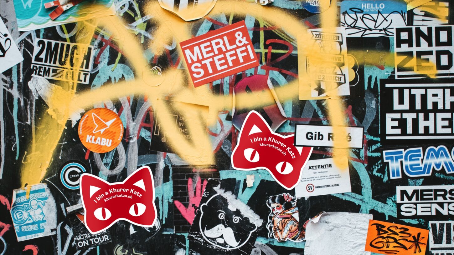 Sticker der Kampagne Kuhrer Katza auf einer vollgeklebten Wand.